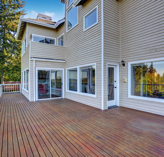 Two Story House With Wooden Walkout Deck Overlooking Backyard
